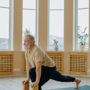 Senior man practicing yoga indoors using blocks for balanced wellness and healthy living.