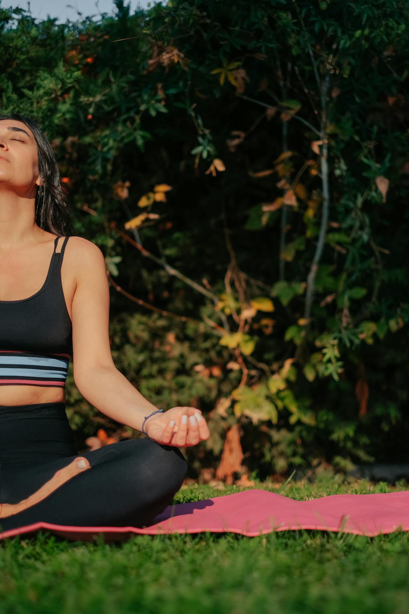 Woman meditating outdoors on yoga mat in sunny park, embracing tranquility